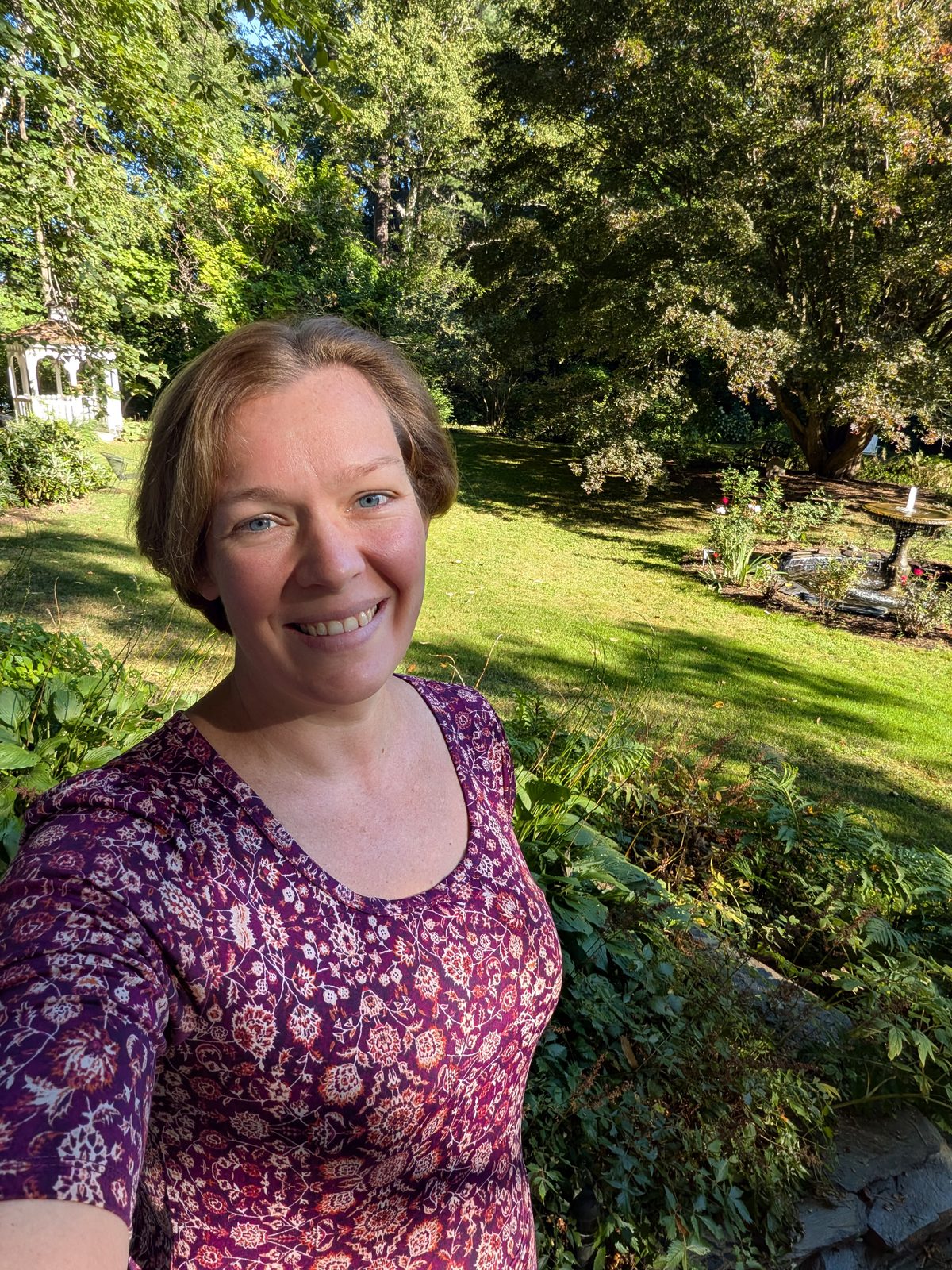 Virginia Haskell, standing outdoors in the garden beside her studio.