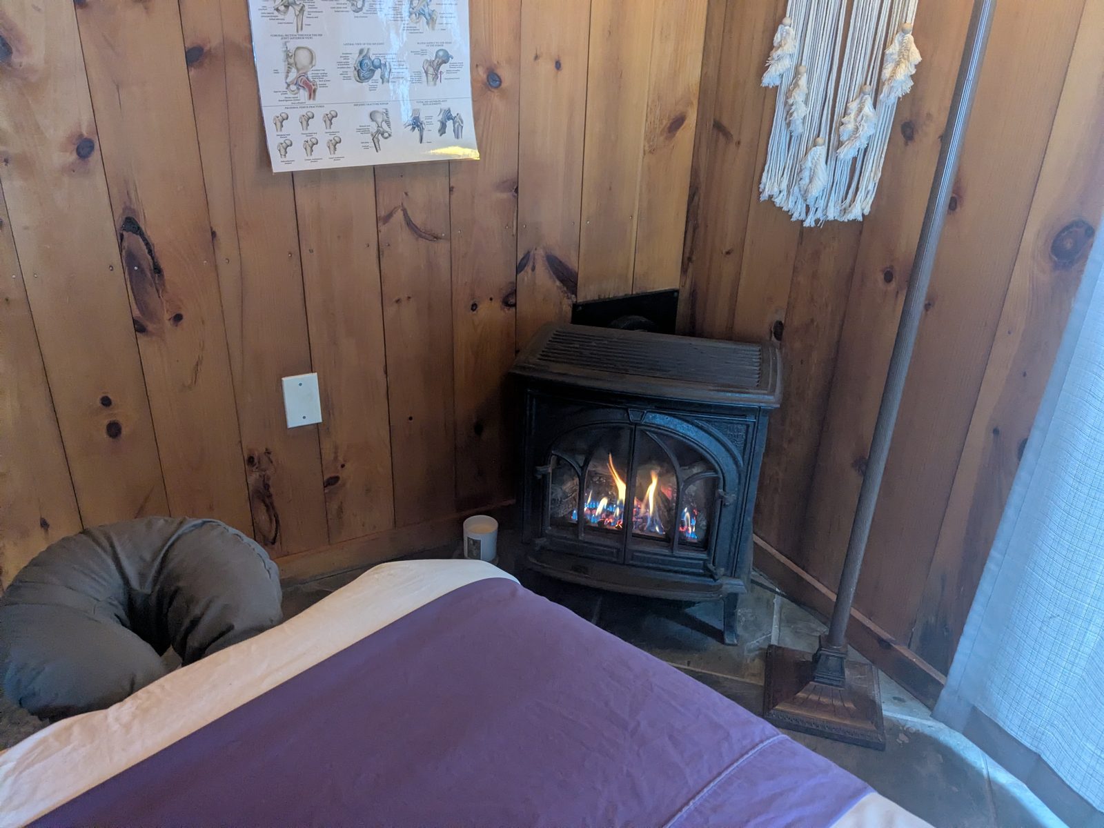 A lit gas stove in the corner of the treatment room, beside the table.